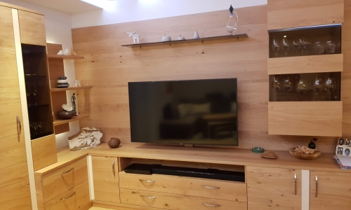 Holz-Wohnzimmerverbau mit Laden, Glasvitrinen und Fernseher.
