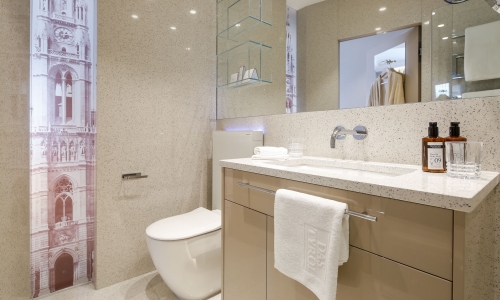 Modernes Badezimmer in Beigetönen mit Spiegel, Ablageflächen und WC.