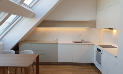 Eine moderne Küche unter einer Dachschräge mit Panoramafenstern.