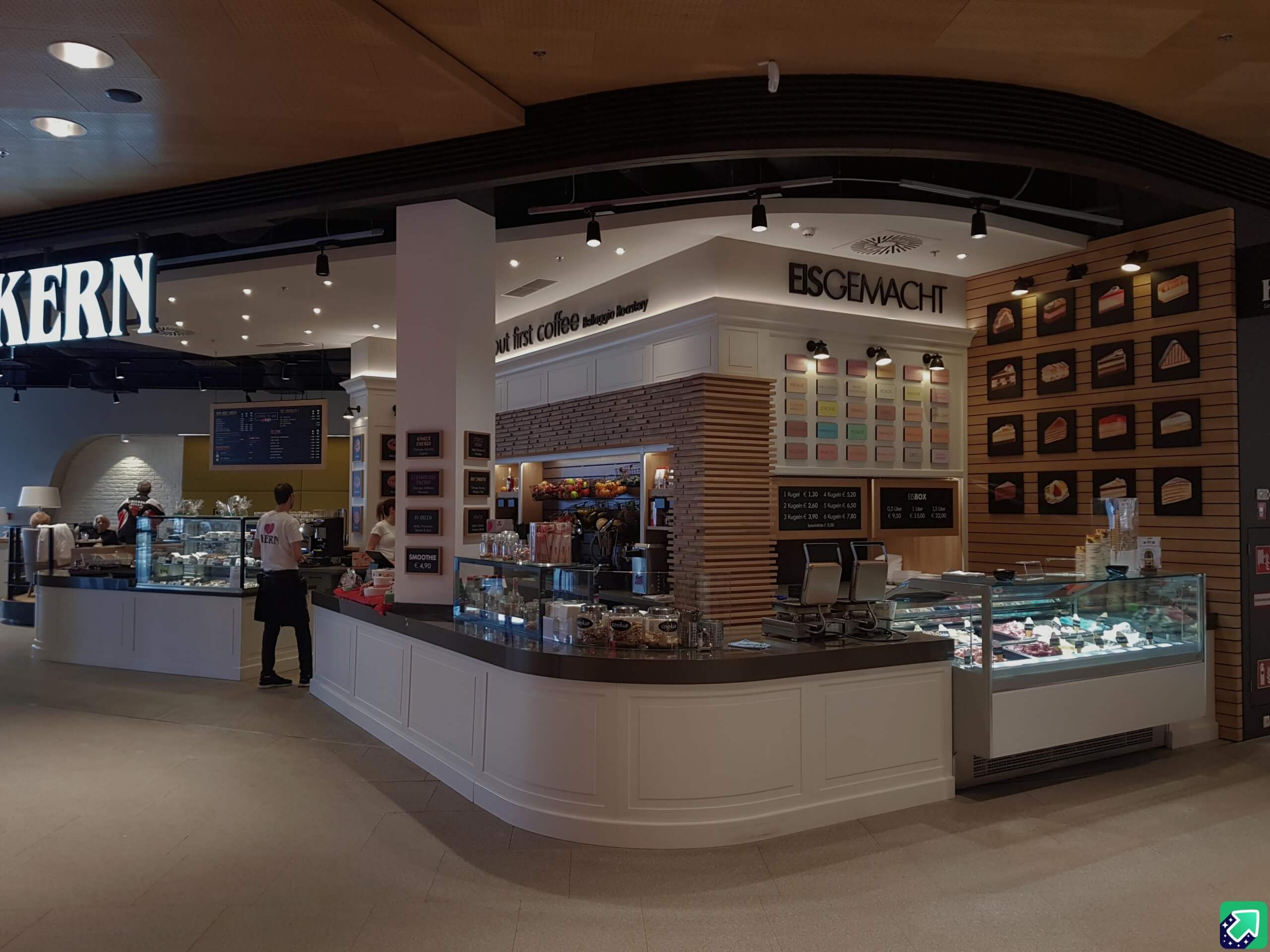 Modernes Café mit integriertem Eissalon – stilvolle Einrichtung, große Eistheke und Wanddekoration mit Eissorten und Tortenstücken.