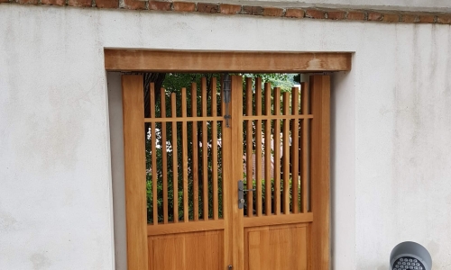 Ein zweiflügeliges Holz-Gartentor als Durchgang.