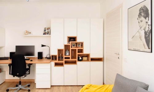Helles Arbeitszimmer mit ergonomischem Schreibtisch, großem Stauraumschrank mit offenen Holzfächern und dekorativen Elementen – funktional und stilvoll zugleich.