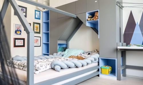 Verspieltes Kinderzimmer mit integriertem Hausbett, grauen und blauen Schrankelementen, liebevoller Deko und viel Stauraum.