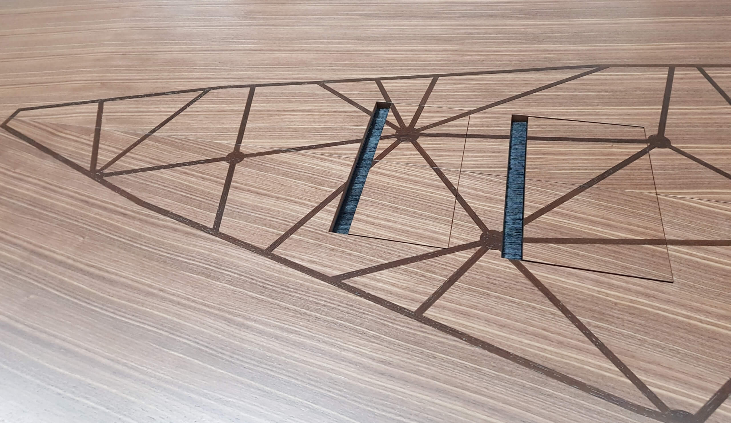 Detailaufnahme einer Holzplatte mit geometrischem Intarsienmuster und zwei herausnehmbaren rechteckigen Elementen – präzise CNC-gefräst.