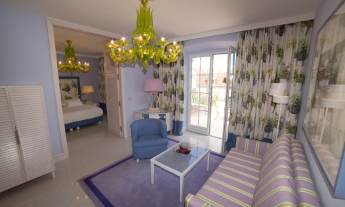 Ein Hotelzimmer in Blautönen mit Terrasse und Sitzgruppe.